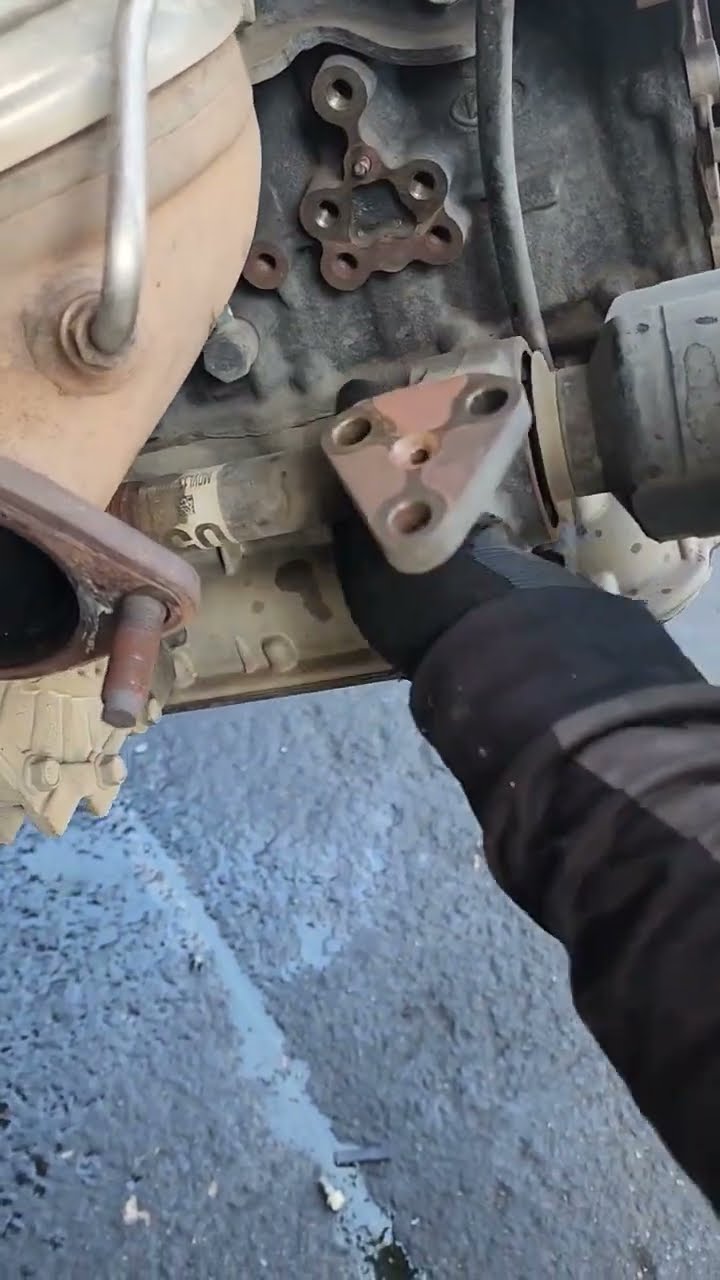 Gloved hands using hand tools to work on a vehicle component and housing.