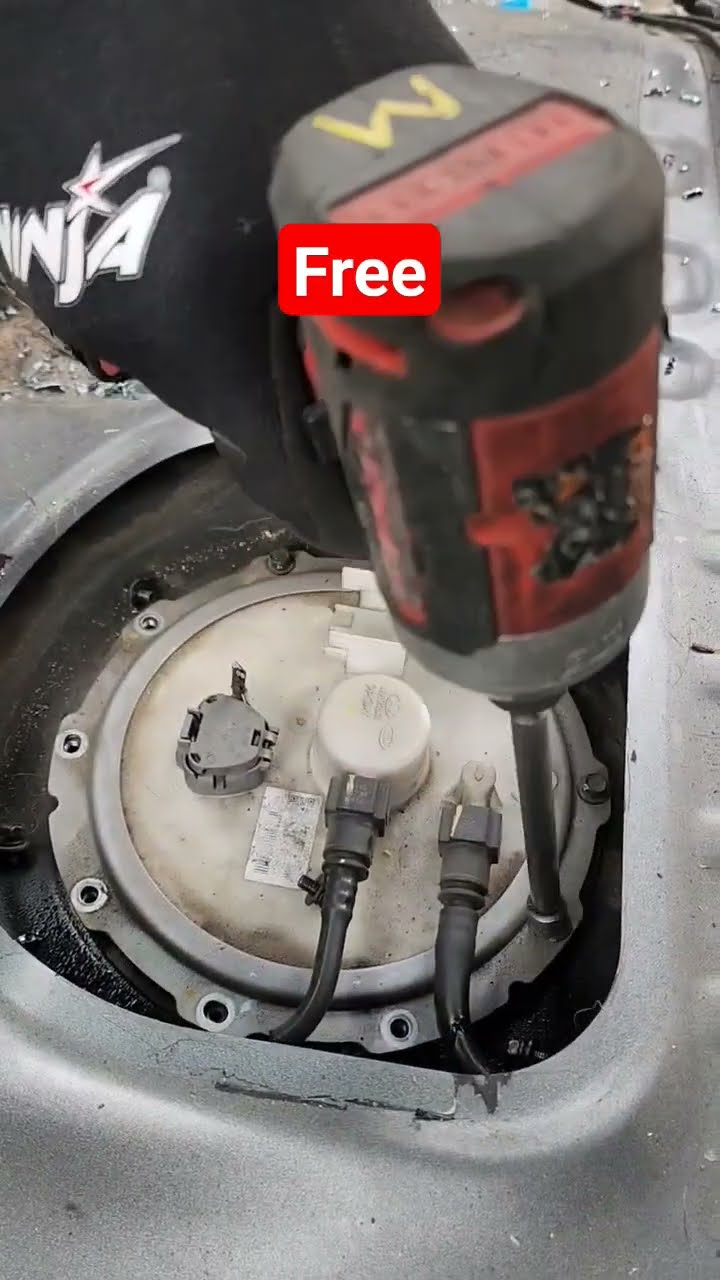 A power tool above the exposed circular fuel-pump access in a car.